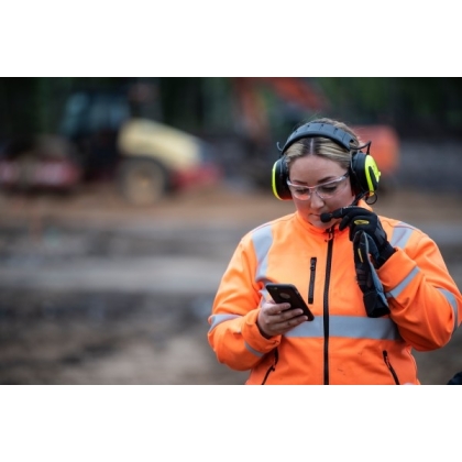 MRX21A4WS6, PELTOR, colore giallo fluo, cuffie attive da bardatura temporale, con operatrice che le utilizza in un cantiere